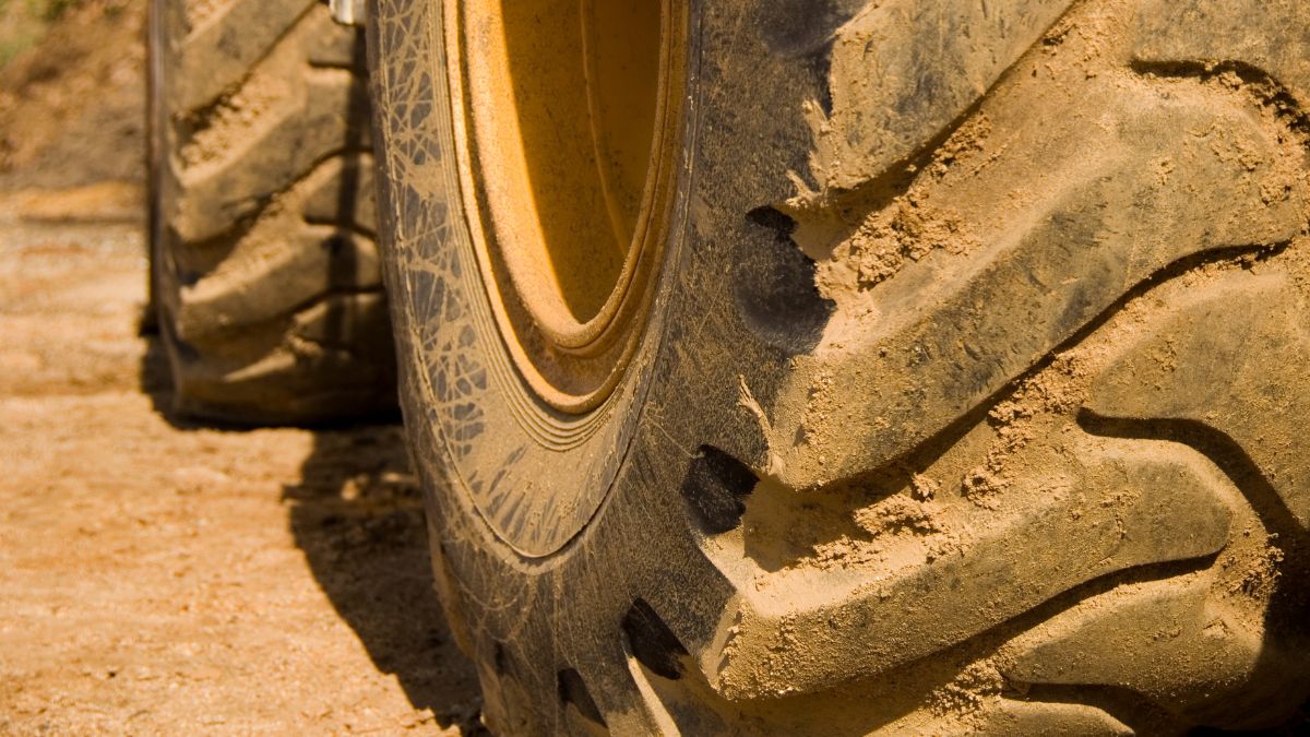 A muddy tractor tire on a track